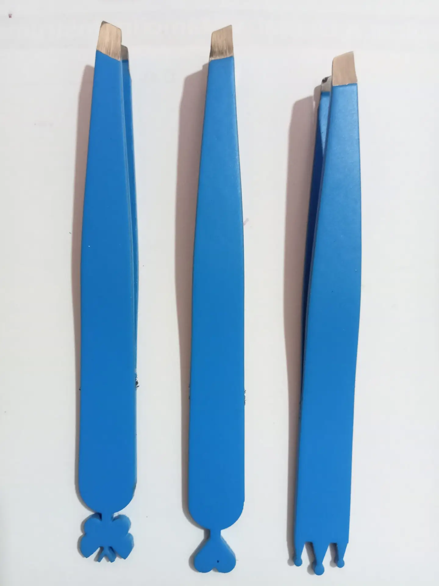Three blue slant tip tweezers with stainless steel tips displayed on a white background